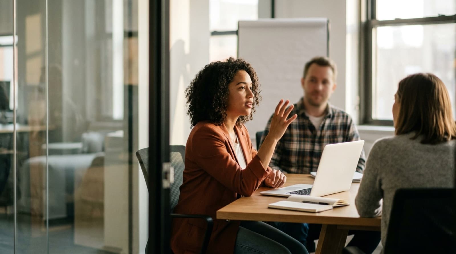 A project manager making a point mid-sentence in a glass-walled meeting room